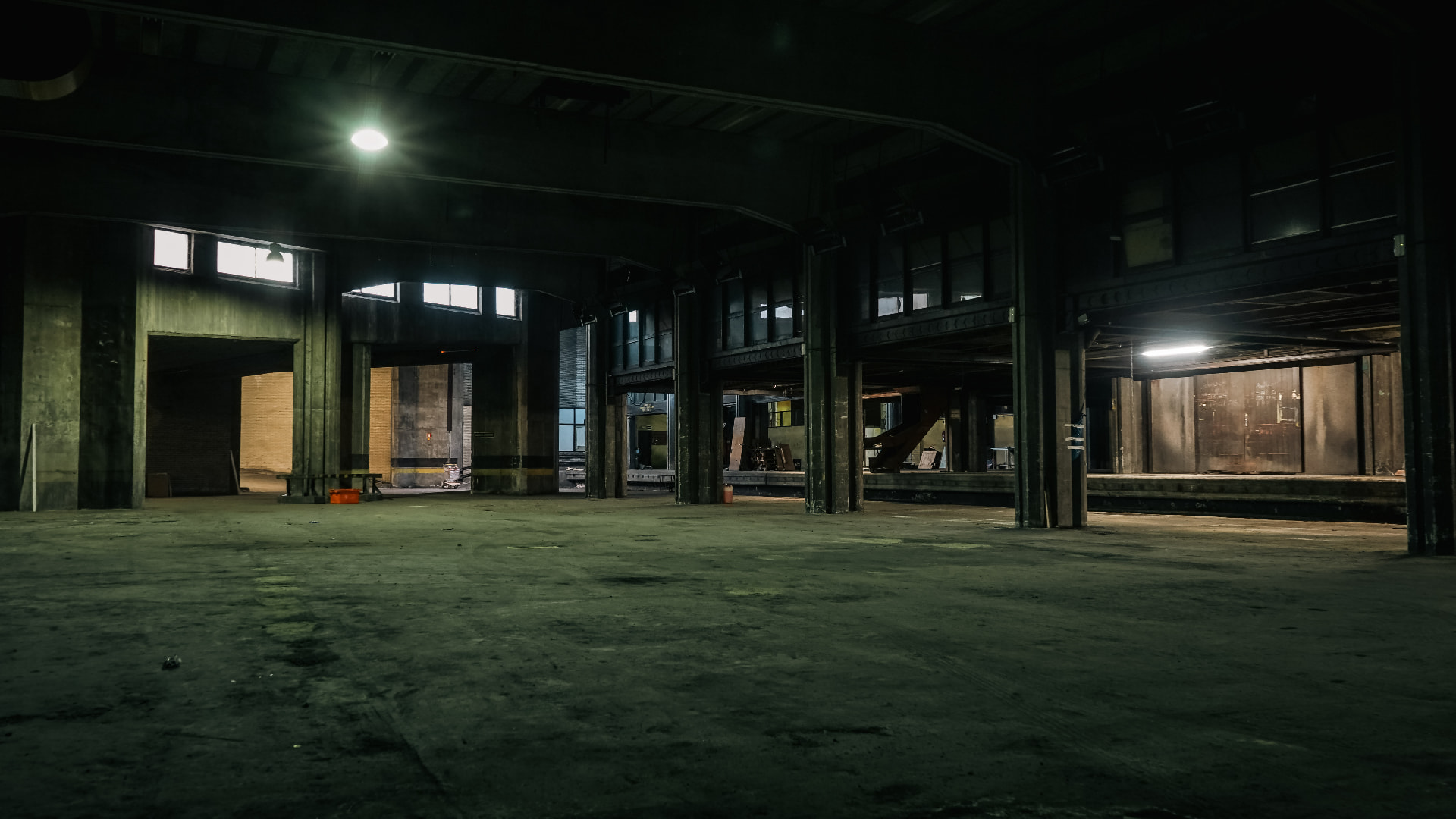 Nave industrial oscura con columnas y luz cenital